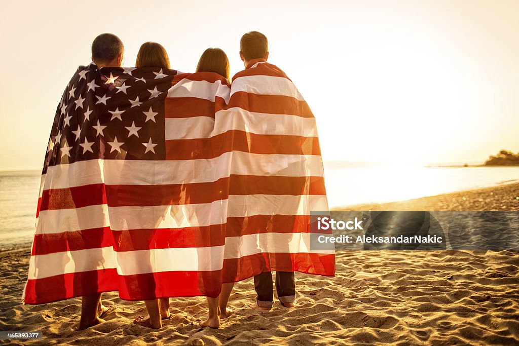 Proud Americans Four people wrapped in the United States Flag embracing each other Fourth of July Stock Photo