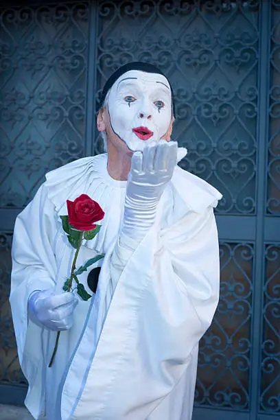 Pierrot with red rose blowing a kiss, San Zaccaria Square, 2013 Carnival Venice, Italy. Flash used.