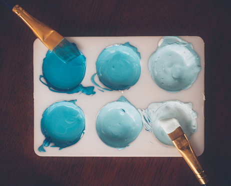 Paint palette with paint colors in various shades of teal