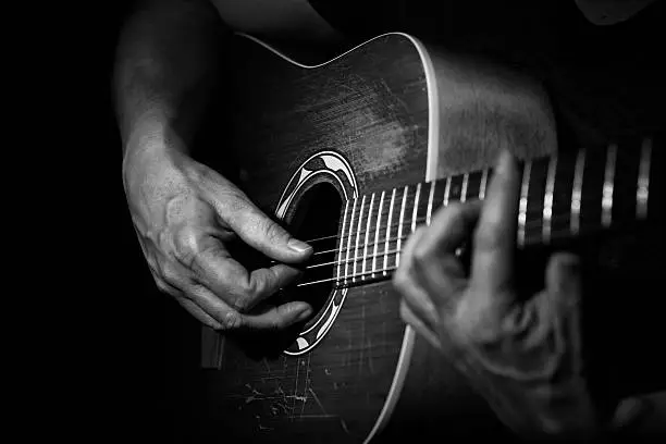 Black and white Picture . Close up of a guitarplayer . The Hand of the player looking aged. High contrast.