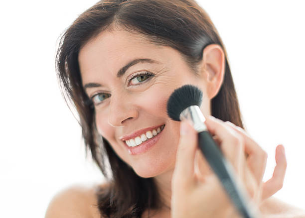 atraente mulher aplicar maquiagem na sua forties - brushing women make up ceremonial makeup imagens e fotografias de stock