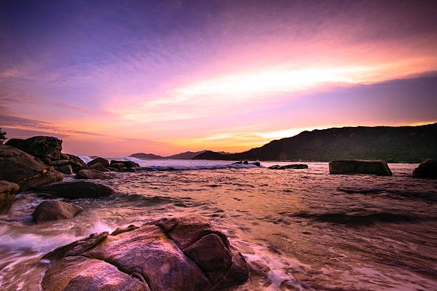 istock Waves crashing on rocky shore in sunset 465404812