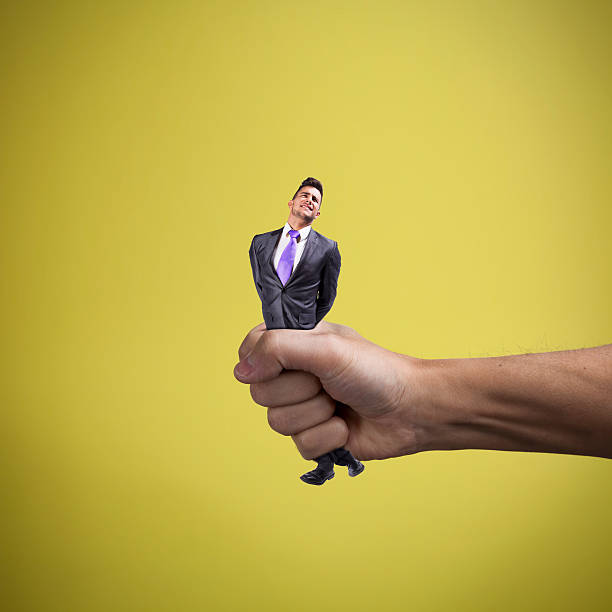 Squeezing the businessman Hand squeezing a young businessman trapped fear people business stock pictures, royalty-free photos & images