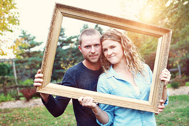 istock Young Couple Peeking Through Picture Frame 465412971