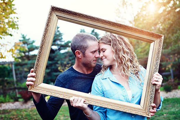 istock Young Couple Peeking Through Picture Frame 465412979