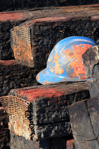 Well used hardhat sitting on a pile of railroad ties.