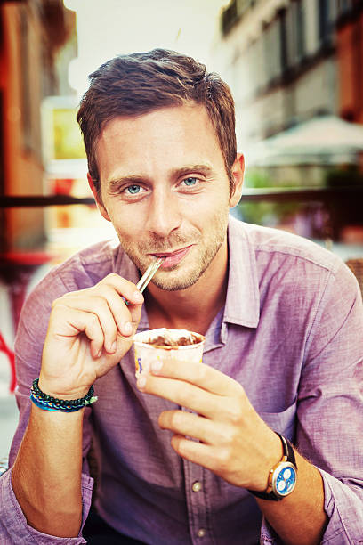 uomo sorridente mangiare una icecream - ice cream parlor ice cream dessert italian culture foto e immagini stock