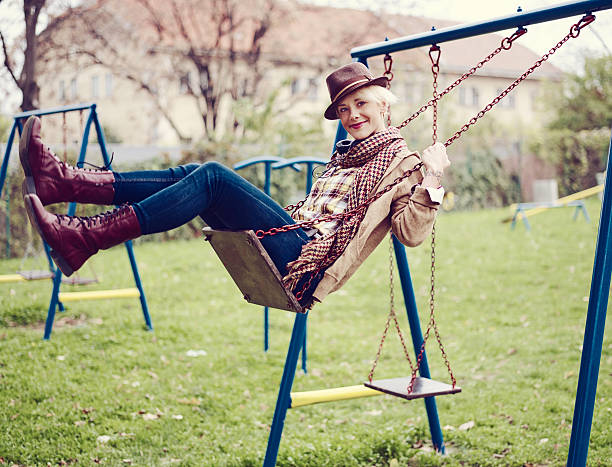 full body shot of young woman on swing in the park