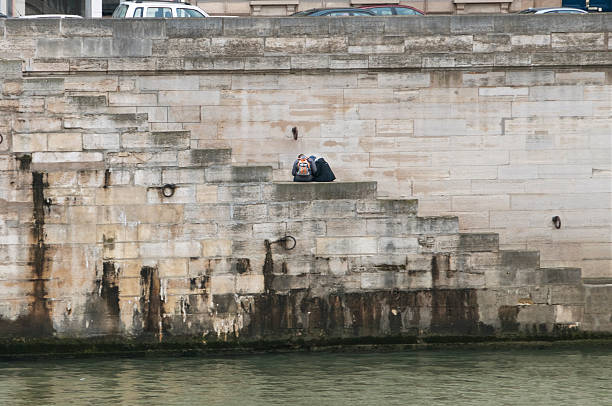 Young couple sitting on stairs to river and consulting map in Paris, France