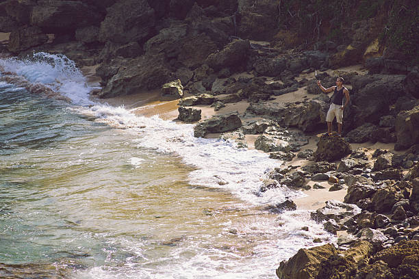 Hispanic man hiking and taking a picture with his smart phone at Cerro Gordo beach  located in Vega Alta, Puerto Rico