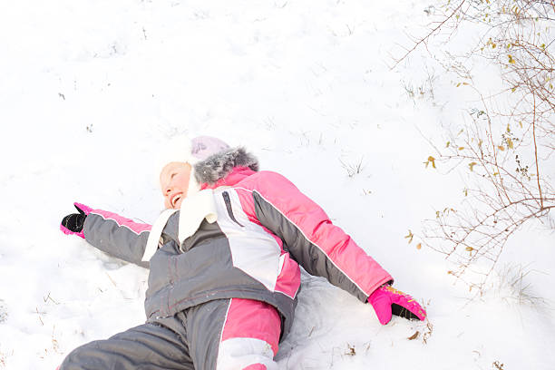 istock Laughing little girl lying in snow 465440957