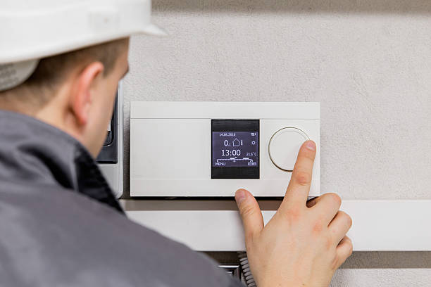 Engineer adjusting thermostat Engineer adjusting thermostat for efficient automated heating system. temperature control stock pictures, royalty-free photos & images