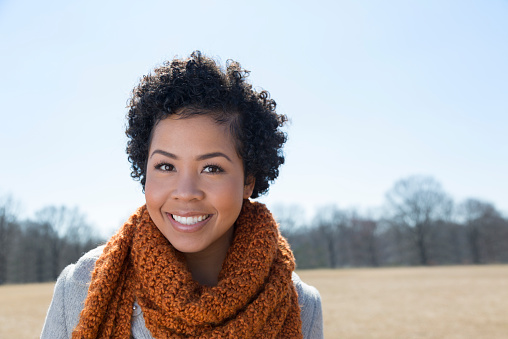 A young mixed race woman in winter clothing outside in a park.