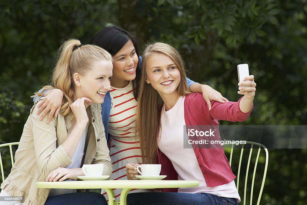 Jeunes filles prenant des photos sur Mobile téléphone au café en plein air - Photo de 14-15 ans libre de droits