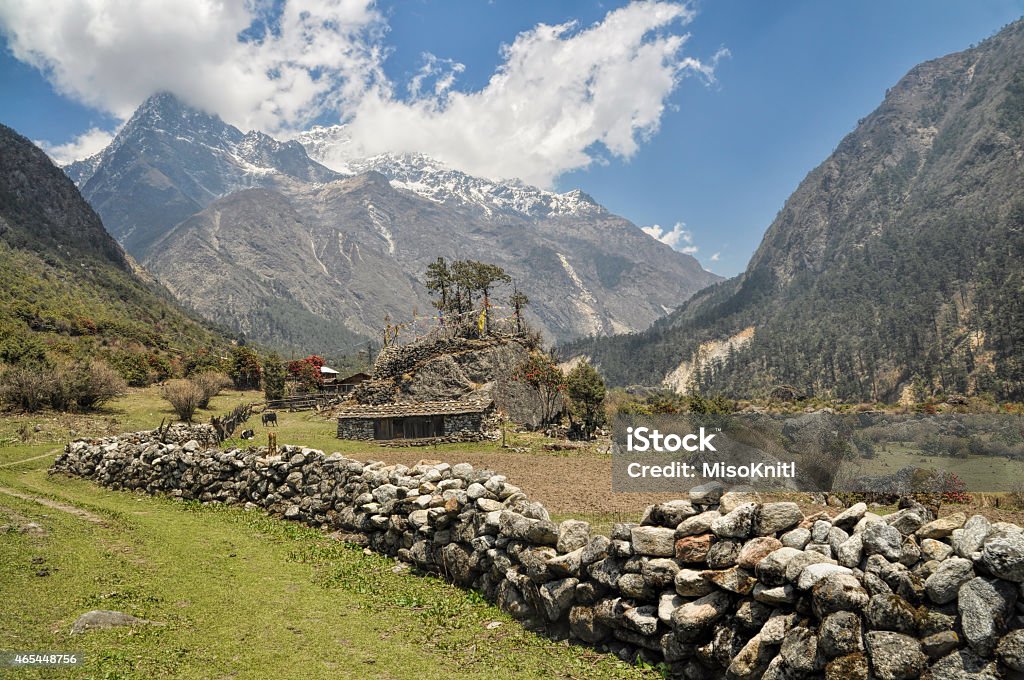 Kangchenjunga Picturesque view of Kangchenjunga rising above a house with a stone wall 2015 Stock Photo