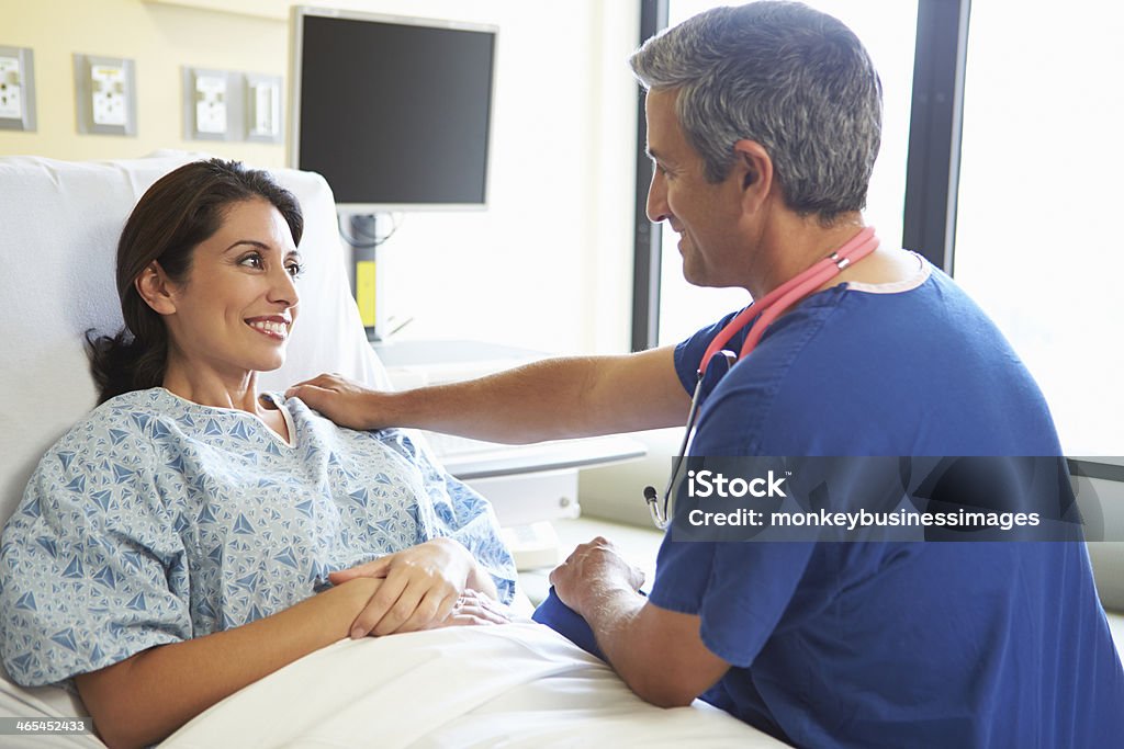 Male nurse speaking to female patient in hospital Happy Male Nurse Talking With Smiling Female Patient In Hospital Room Patient Stock Photo