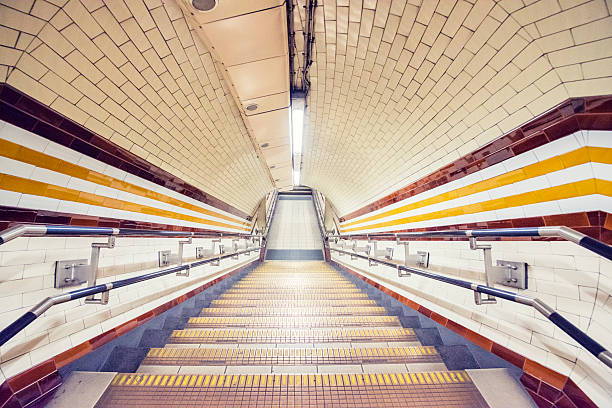 This is a horizontal, color photograph of an empty retro subway station in the London Underground with descending steps.