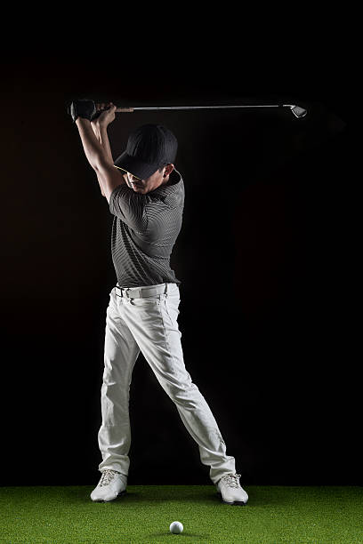 istock Man posing in dark on green with golf club 465455543
