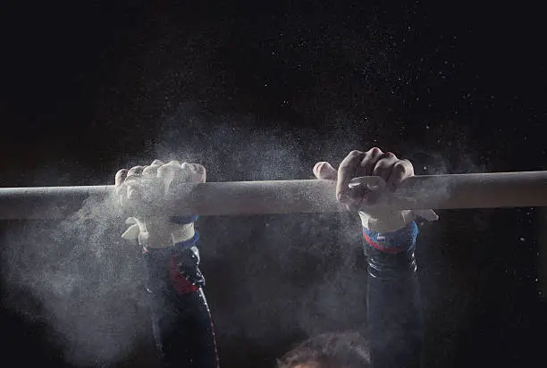 hands of gymnast with chalk on uneven bars