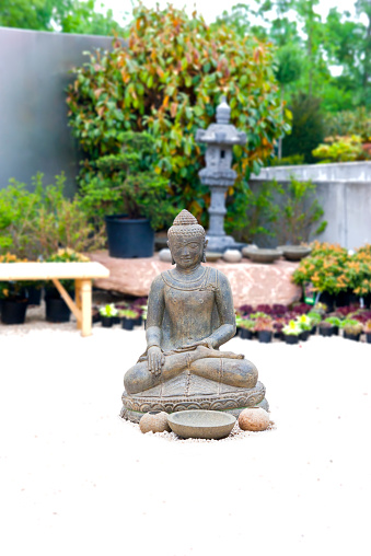 Buddha statue and sculptures in a spiritual garden of an Asian garden designer.