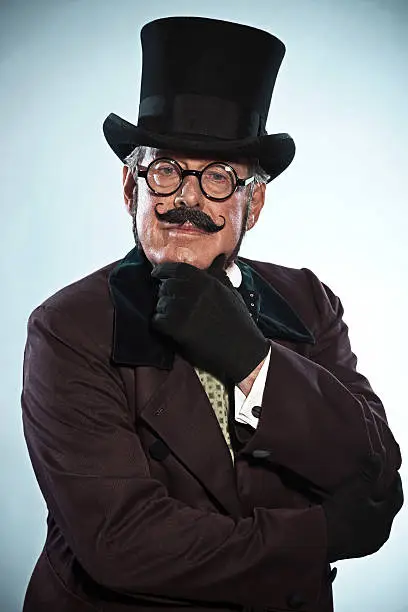 Vintage dickens style man with mustache and hat. Wearing glasses. Studio shot.