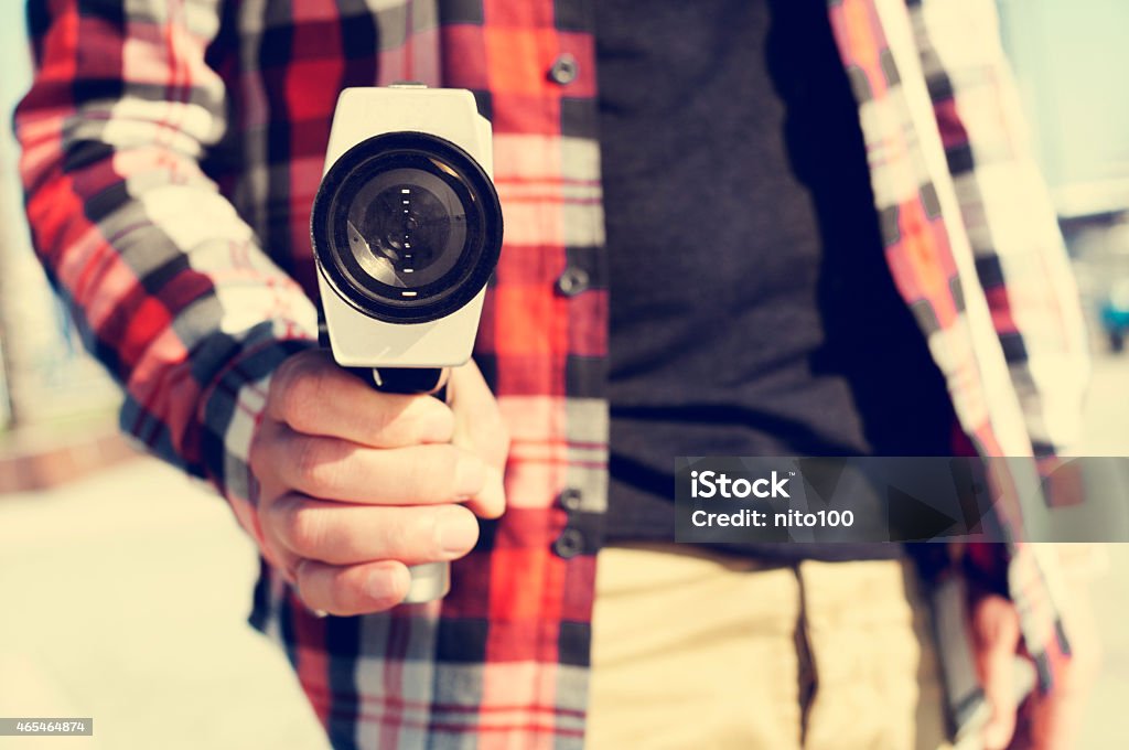 young man pointing a Super 8 camera at the observer closeup of a young man pointing a Super 8 camera at the observer like it was a gun Camera - Photographic Equipment Stock Photo