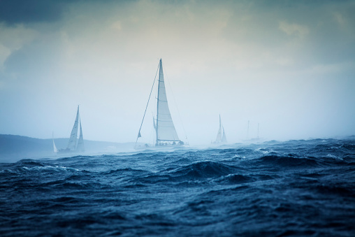 Several sail boats sailing in high tide sea