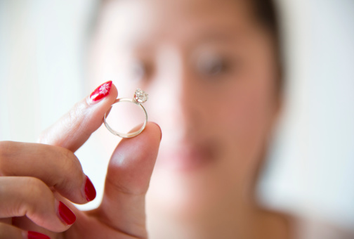 Asian woman holding a wedding ring.