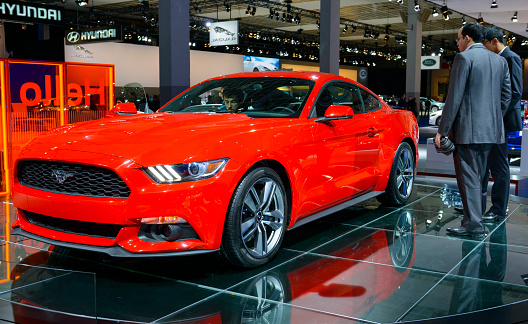 Brussels, Belgium - January 15, 2015: Ford Mustang Muscle Car on display during the 2015 Brussels motor show. Two men are looking at the car and people in the background are looking at the cars.