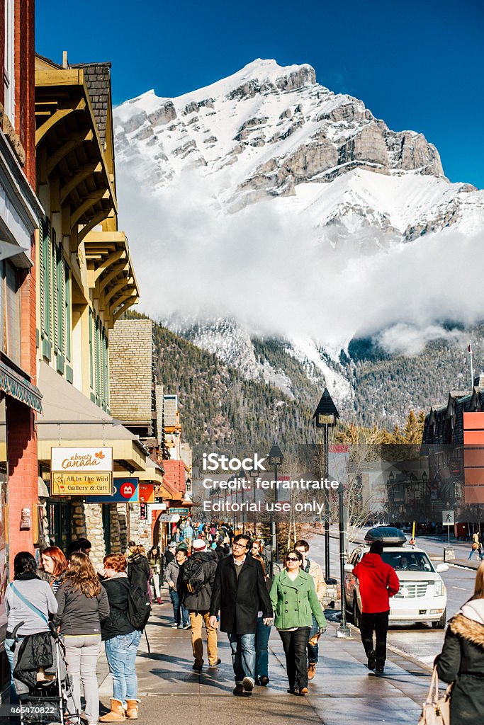 Banff National Park Canada Banff, Canada - February 14, 2015: People walking down the main commercial street in Banff, Banff avenue, with the spectacular view of Mt. Girouard on the Background. Apres-Ski Stock Photo