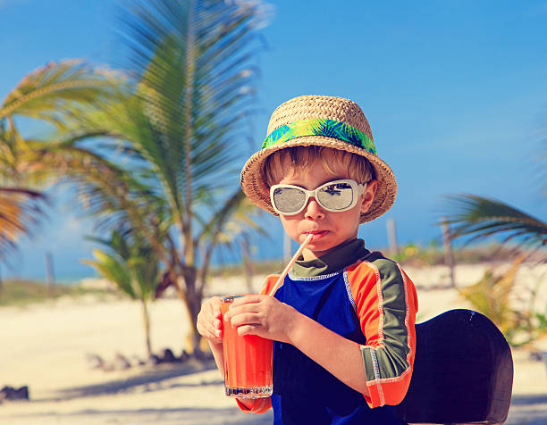 istock cute little boy drinking juice on the beach 465470824