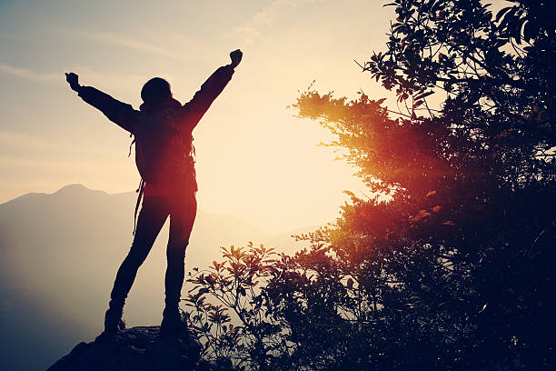 istock cheering woman hiker open arms at mountain peak 465477258