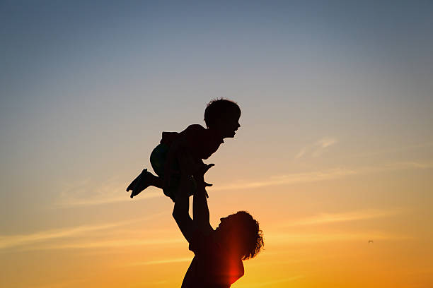 istock father and son silhouettes play at sunset 465478030