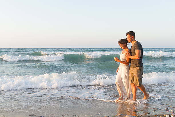 istock Young couple enjoys walking on a hazy beach at dusk 465480436