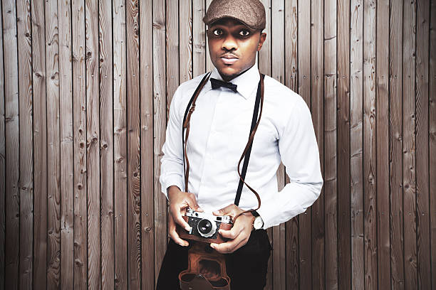 Portrait of a stylish young man with old photocamera