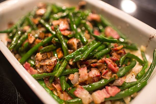 Close up shot of a casserole dish with a green bean vegetable medley, with mushrooms and bacon also. There is a juicy marinade that makes this fresh dish glisten. A great shot for recipes, health food and other cooking related sources. Taken in preparation for the american holiday thanksgiving - A great shot for preparation cookbooks, ingredient, catalogs, chef, diet and cooking websites or magazines.