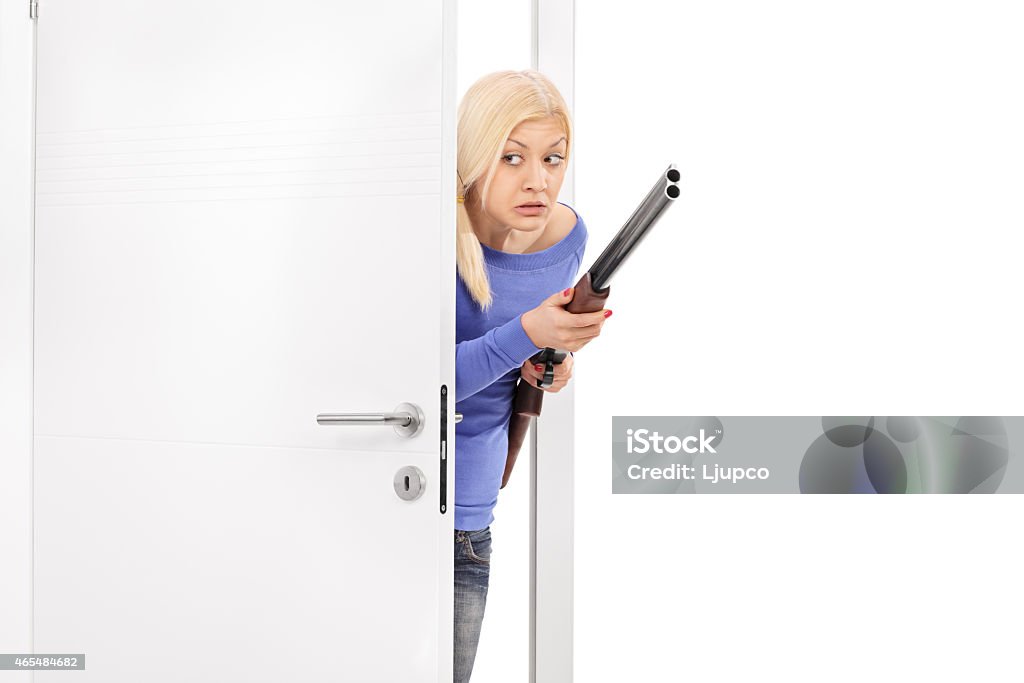 Terrified woman holding a rifle and entering a room Terrified woman holding a rifle and entering a room isolated on white background 20-29 Years Stock Photo