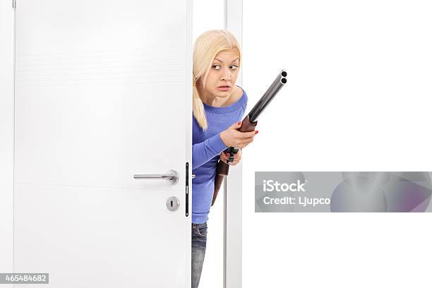 Terrified Woman Holding A Rifle And Entering A Room Stock Photo - Download Image Now