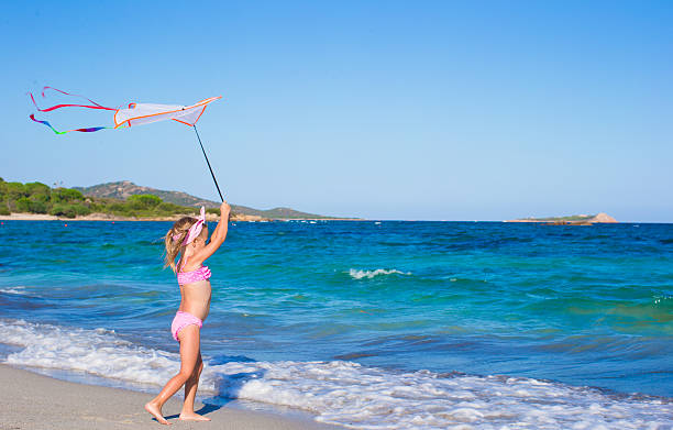 istock Happy girl playing with flying kite during tropical beach vacation 465484720