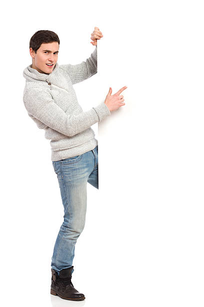 istock Young man in gray sweater pointing at a banner. 465485483