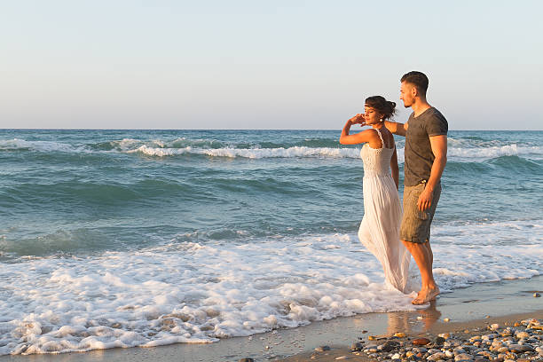 istock Young couple enjoys walking on a hazy beach at dusk 465485662