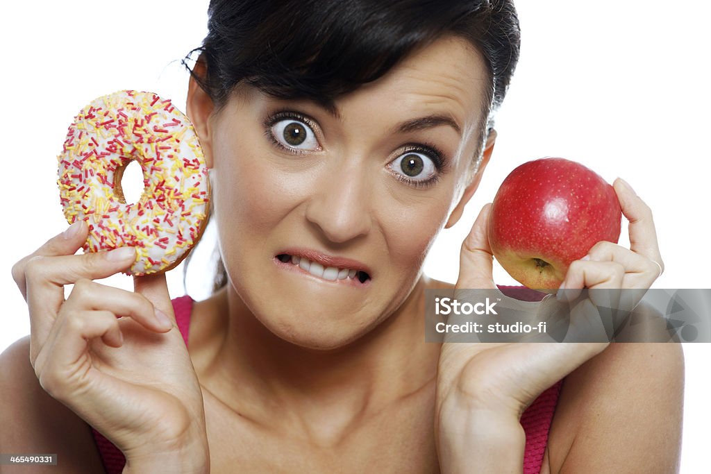 Woman choosing food Young woman deciding between an apple or doughnut. Eating Stock Photo