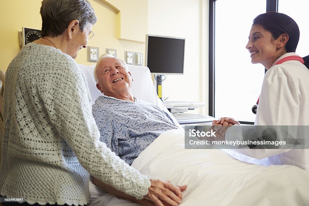 Doctora hablando con pareja Senior en Hospital habitación - Foto de stock de Paciente libre de derechos