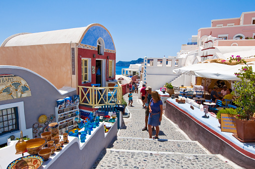 Oia, Santorini, Greece - July 28, 2014: Tourists do shopping in Oia town, local shops display goods for sale.