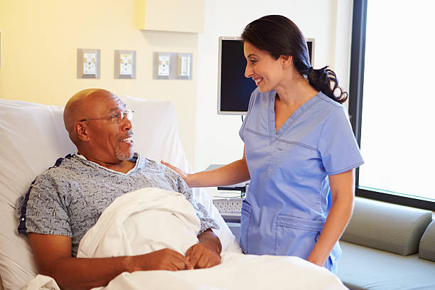 Nurse Talking To Senior Male Patient In Hospital Room Happy Smiling Nurse Talking To Senior Male Patient In Hospital Room patience stock pictures, royalty-free photos & images