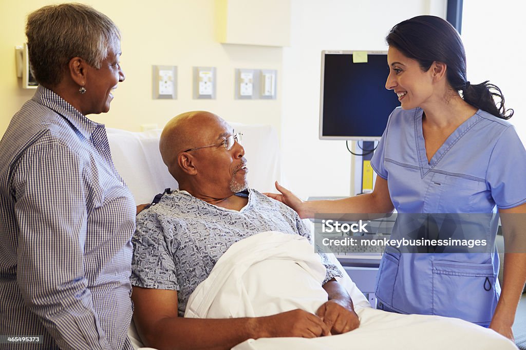 Nurse Talking To Senior Couple In Hospital Room Happy Smiling Nurse Talking To Senior Couple In Hospital Room Bed - Furniture Stock Photo