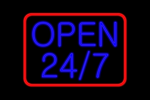Illuminated Neon sign with blue Letters and red frame showing open 24 7 isolated on black background