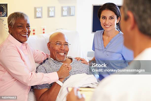 Medical Team Meeting With Senior Couple In Hospital Room Stock Photo - Download Image Now