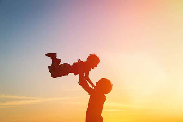 istock father and son silhouettes play at sunset 465497334