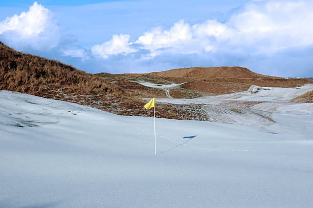 snowfall covered links golf course with yellow flag stock photo